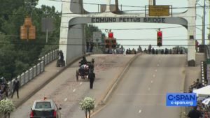 The funeral carriage viewed from behind as it crosses the bridge.