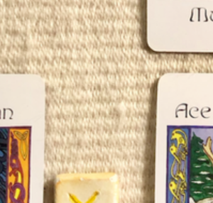 A teaser shot showing just the corners of the cards and one part of a rune from this week’s reading.