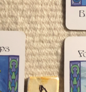 A teaser shot showing just the corners of the cards and one part of a rune from this week’s reading.