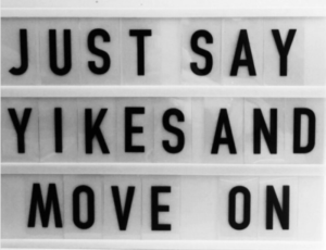 A white signboard with black letters spelling out, "Just say Yikes and Move On".