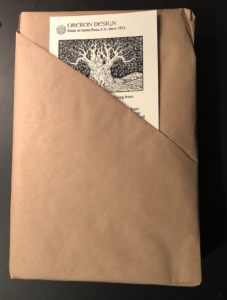 A decorated notecard peeking out of the edge of brown paper wrapping on a book.