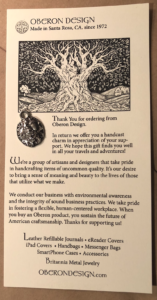 The notecard with a silver charm on it.