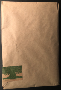 A sticker with a drawing of a tree and the words "Oberon Design Thanks You" sits near the bottom of a brown paper wrapped rectangle.