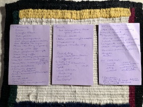 Three purple index cards with handwritten lists on them.