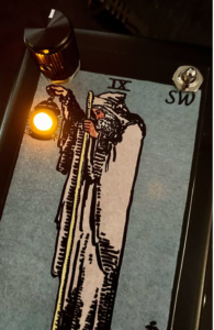 A guitar pedal with the Rider-Waite-Smith Hermit figure on it. The pedal light shines in the Hermit's lantern when lit.