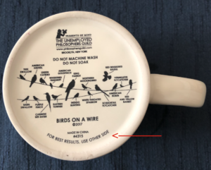 The bottom of a coffee cup, with various words and images. At the lower edge of the cup, a red arrow has been added, pointing to the words, "For best results, use other side."