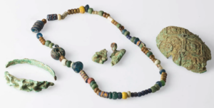 A photo of some of the jewelry, including a beaded necklace and pieces of a turtle brooch.